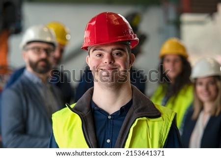 Young man with Down syndrome working in industrial factory, social integration concept. Royalty-Free Stock Photo #2153641371