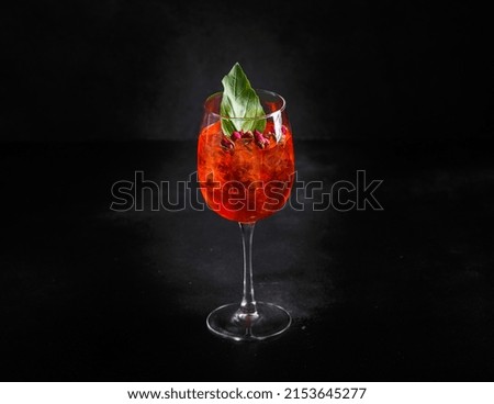 Alcoholic cocktail with red ice with fruits and berries. Dark background, copy space