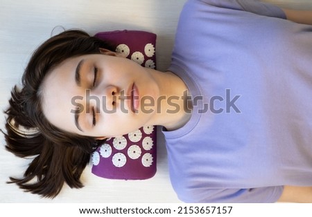 Acupuncture massage mat with pillow. Teenage girl lies on a massage mat.Concept of alternative medicine. Acupuncture massage mat with pillow. Royalty-Free Stock Photo #2153657157