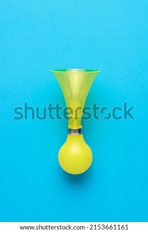 Retro bicycle horn in yellow on a blue background. An accessory for warning about danger. Flat lay.