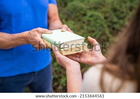 Sharing Books. Hand Closeup Giving Book Outdoors Royalty-Free Stock Photo #2153664561