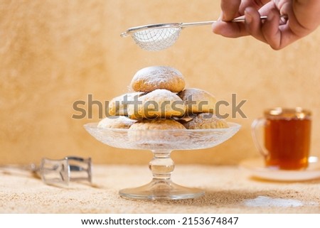 traditional Islamic Feast,Cookies for celebration of Eid El Fitr (Kahk) dusted with fine sugar with a cub of tea in the background  Royalty-Free Stock Photo #2153674847