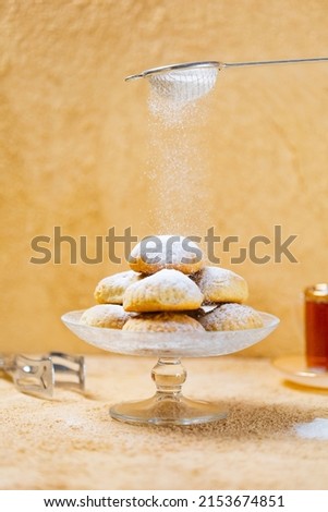 traditional Islamic Feast,Cookies for celebration of Eid El Fitr (Kahk) dusted with fine sugar with a cub of tea in the background  Royalty-Free Stock Photo #2153674851