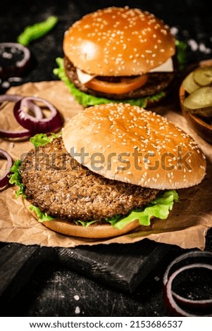 Delicious burger with lettuce leaves and onion rings. On a black background. High quality photo