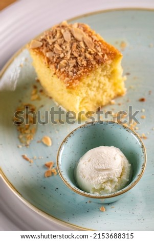 A piece of sponge cake with ice cream on a blue plate. Restaurant. Table with marble.