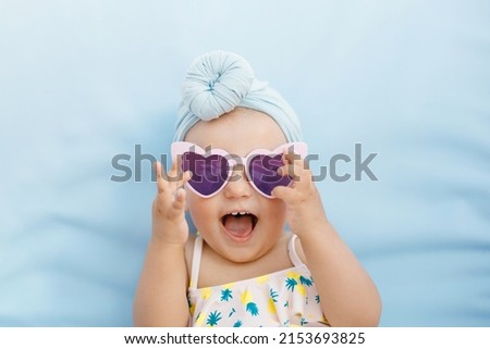 Funny cute baby girl on summer vacation. Child having fun in swimming pool. Sweet toddler girl in colorful swimsuit and sunglasses relaxing on sunbed. Royalty-Free Stock Photo #2153693825