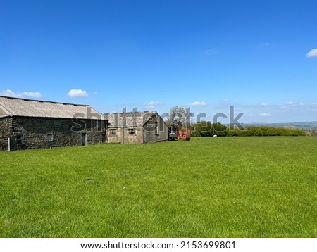 Old farm buildings and machinery, in a large field, with hills in the far distance near, Cowling, UK