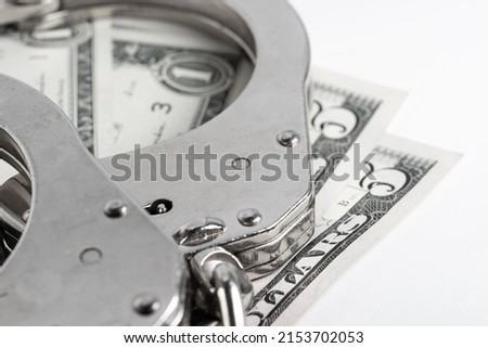 Police handcuffs lie on dollar bills. Crime, justice and money. Crime and corruption concept with handcuffs.
