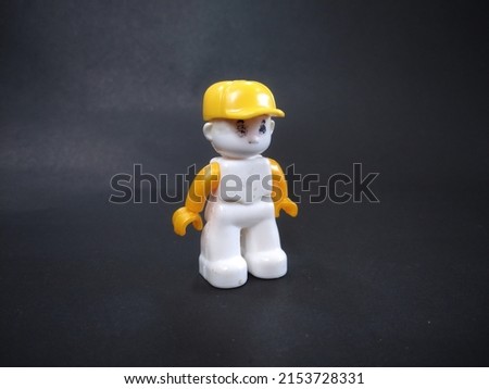 person figure in lego game wearing yellow hat standing position, black background