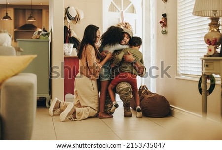 Happy soldier reuniting with his wife and children after serving in the army. Cheerful serviceman embracing his family after returning home. Military man receiving a warm welcome from his family. Royalty-Free Stock Photo #2153735047