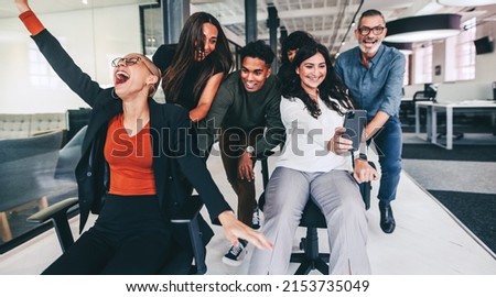 Snapping the best work moments. Happy businesswoman taking a selfie with her colleagues during playtime. Group of businesspeople having fun and celebrating their success in a modern office. Royalty-Free Stock Photo #2153735049