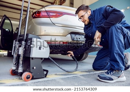 An auto-mechanic checking on car exhaust gases on technical service. Royalty-Free Stock Photo #2153764309