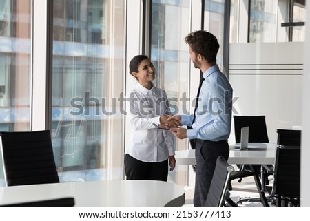 Two diverse confident business man and woman shaking hands in office meeting room. Employer hiring candidate after job interview. Client greeting manager, lawyer with handshake. Negotiation concept Royalty-Free Stock Photo #2153777413