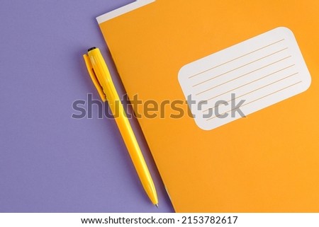 A bright yellow school diary or a mock-up notebook and a yellow pen on a blue-purple background.The concept of teacher's day, things for businessmen, schoolchildren, education, planning.Copyspace