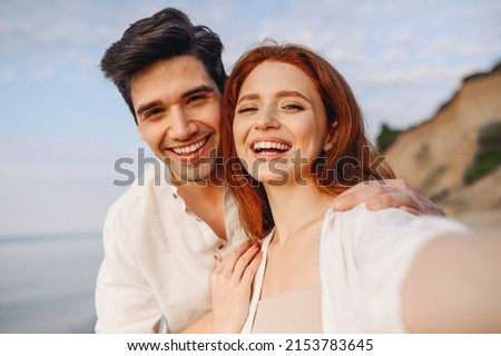 Close up smiling happy young couple two family man woman in casual clothes hug each other doing selfie shot pov on mobile phone at sunrise over sea beach outdoor seaside in summer day sunset evening.