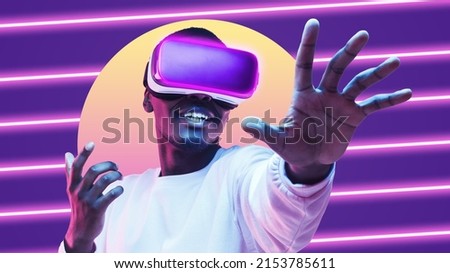 Amazed african american man wearing vr goggles, playing in metaverse virtual world as super hero, touching something invisible in neon light Royalty-Free Stock Photo #2153785611