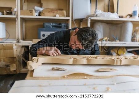 carpenter working on a bas-relief in the workshop