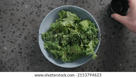 Top view massaged kale leaves in blue ceramic bowl on concrete background, wide photo