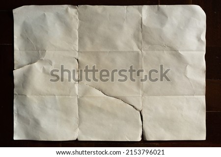 Old off white folded paper on dark wood background Royalty-Free Stock Photo #2153796021