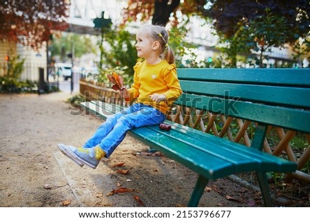 Adorable three years old girl sitting on a bench on a street in Paris, France