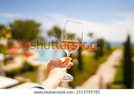 Female hand with glass of r wine. Cozy hotel on the coast of Lagos. Sea view, beautiful landscape in Portugal Adventure in Europe (travel photo).