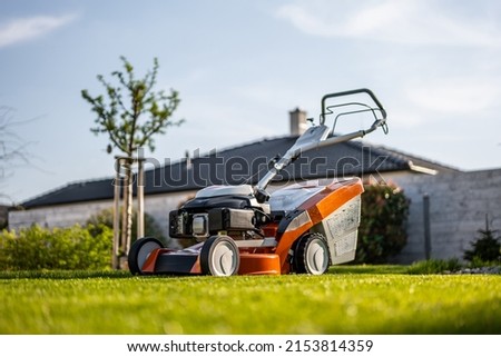 Lawn mover on green grass in modern garden. Machine for cutting lawns. Royalty-Free Stock Photo #2153814359