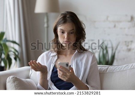 Shocked concerned cellphone user girl staring at screen, looking at smartphone screen, finding problems with online app, poor connection, Internet service, getting surprising bad news Royalty-Free Stock Photo #2153829281