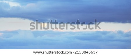 Full moon in a clear blue sky with colorful pink sunset cumulus clouds. Dramatic cloudscape. Natural phenomenon, meteorology, hope, heaven, peace, mystery, moonlight, twilight. Panoramic image Royalty-Free Stock Photo #2153845637