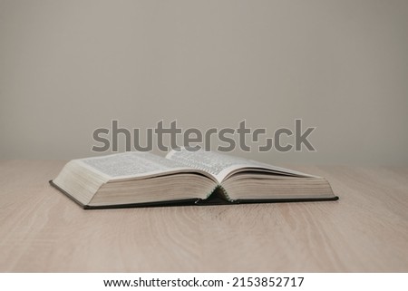 Open holy bible on a  wooden table. Beautiful white wall background. Royalty-Free Stock Photo #2153852717
