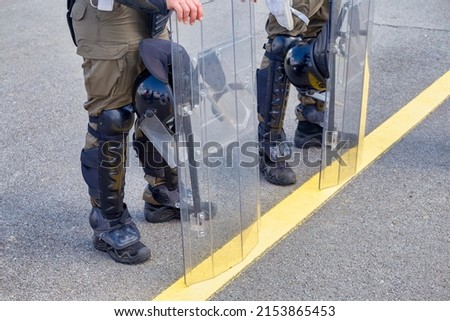 Military police officers members lined up with protective gear, securing the zone during a manifestation.