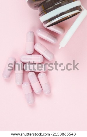 The Pink capsule pills with bottle on pink background 