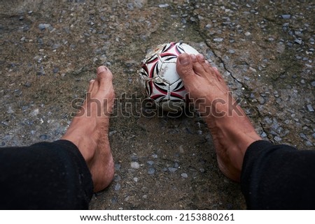 Close up picture of man playing football on field. Old male bare feet having fun with football ball. Sport and man development concept. 