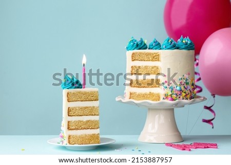 Birthday cake with layers and turquoise frosting, slice removed and one pink birthday candle