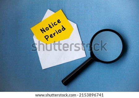 Notice period text on notepad in an envelope with magnifying glass on blue background. Employment concept Royalty-Free Stock Photo #2153896741