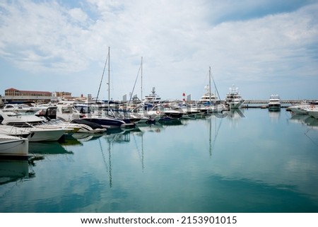 Yacht parking in harbor. Beautiful Yachts in blue sky background. Sailing harbor, many beautiful moored sailing yachts in the seaport, summer vacation, luxury lifestyle and wealth concept.