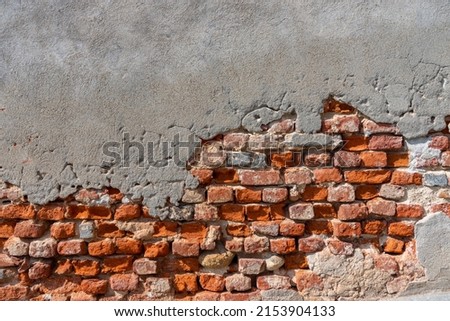 Wall texture with ancient plaster and peeling background with exposed red brick and concrete. Ideal for background with copy space Royalty-Free Stock Photo #2153904133