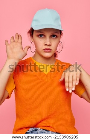 pretty girl in an orange sweater in blue caps hand gesture cropped view unaltered