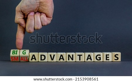 Big or small advantages symbol. Businessman turns wooden cubes, changes words Small advantages to big advantages. Beautiful grey background, copy space. Business, small or big advantages concept.
