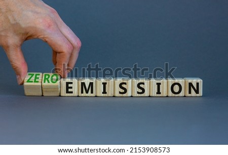 Zero emission symbol. Businessman turns wooden cubes and changes words Emission to Zero emission. Beautiful grey background. Business, ecological and zero emission concept. Copy space.