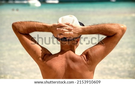 Back view of a man wearing straw hat on the shoreline. Holiday concept