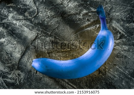 blue banana on a gray background, blue and gray color, banana creative photo, sun rays
