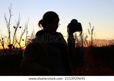 silhouettes of girl with camera at sunset.