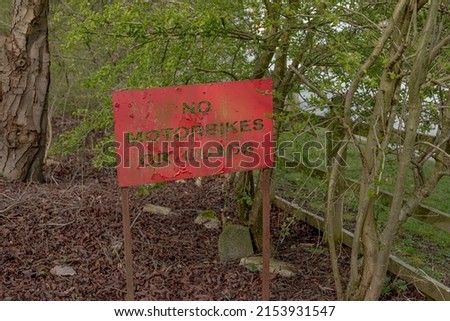 Red metal sign at the start of a trail in rural cheshire asking users not to enter on motorbikes or quads