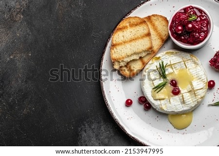 Baked camembert cheese with cranberries, basil leaves and rosemary on dark table. French cuisine. place for text, top view. Royalty-Free Stock Photo #2153947995