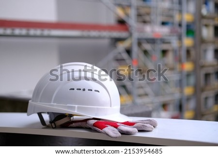 white hardhat, work gloves, helmet on background of buildings, protection inspecting at construction site, symbol of builder's death, day of mourning, civil engineering concept, builder's day Royalty-Free Stock Photo #2153954685