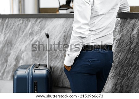 Unrecognizable businessman standing with luggage suitcase in hotel lobby