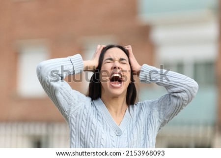 Front view portrait of a mad woman yelling in the street Royalty-Free Stock Photo #2153968093