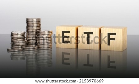 ETF - text on wooden cubes on a cold grey light background with stacks coins