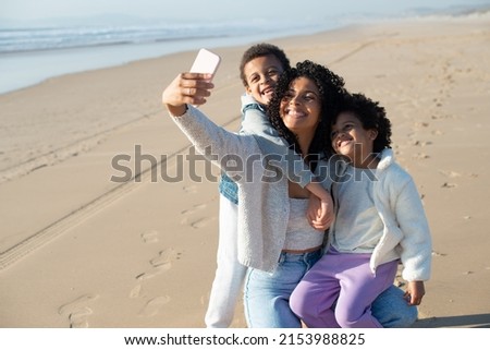 Mother and children taking selfie on beach. African American family spending time together on open air, taking pictures with mobile phone. Leisure, social media, parenting concept