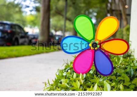 Rainbow garden pinwheel by suburban sidewalk outside home Royalty-Free Stock Photo #2153992387